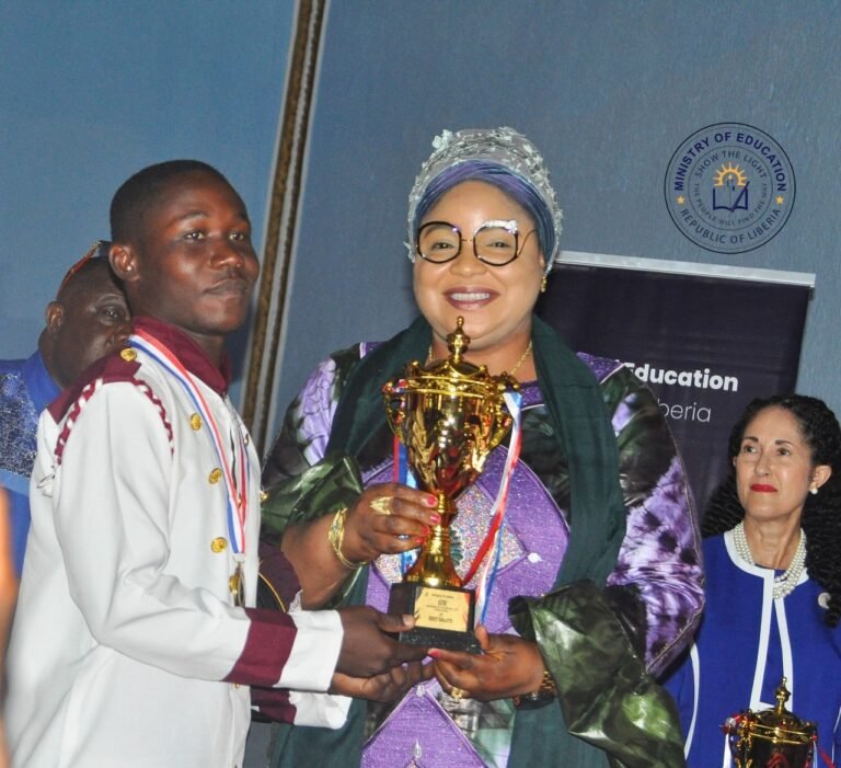Acting Minister of State Mamaka Bility hands over a trophy at the 178th Flag Day celebration in Monrovia